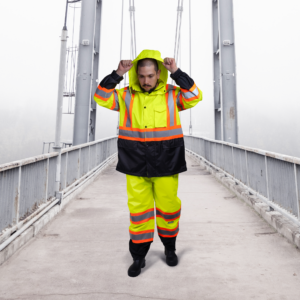 Trabajador usando el conjunto impermeable de seguridad bicolor amarillo en un día nublado sobre un puente.