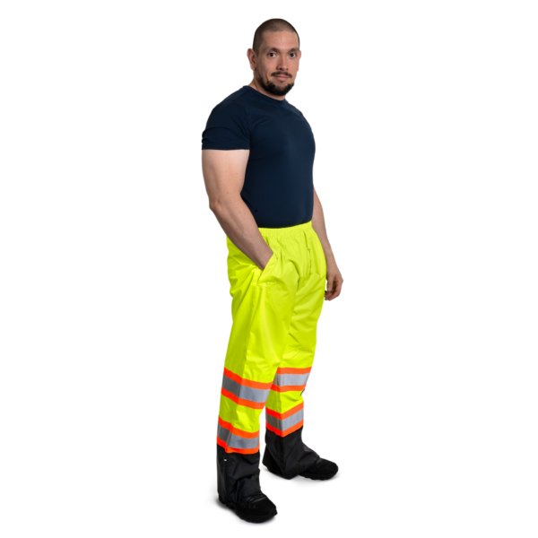 Hombre que lleva pantalones impermeables de seguridad de alta visibilidad bicolor con rayas reflectantes y contrastantes para protección vial