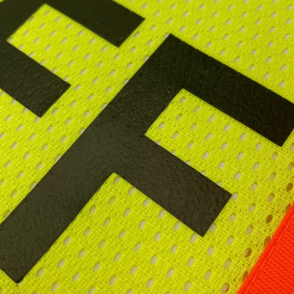 Primer plano del chaleco de seguridad amarillo con bandas reflectantes y tejido de malla para trabajadores del personal