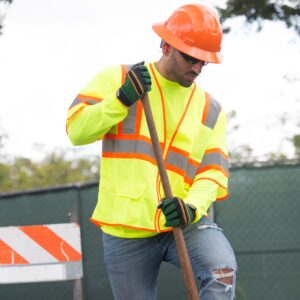 Trabajador con un chaleco de seguridad color lima para protección vial mientras trabaja en una obra de construcción.