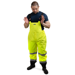 Trabajador que lleva pantalones de trabajo tipo peto de seguridad de alta visibilidad en amarillo y negro con franjas reflectantes