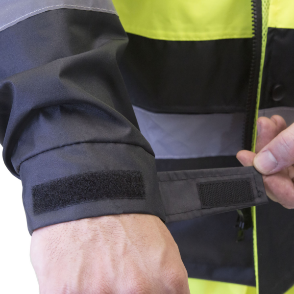 Hombre cerrando la correa del puño ajustable en tamaño de la chaqueta impermeable de alta visibilidad. Para trabajos en carretera