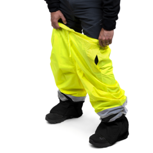 Una persona poniéndose los pantalones impermeables de seguridad JORESTECH amarillos y negros con tiras reflectantes