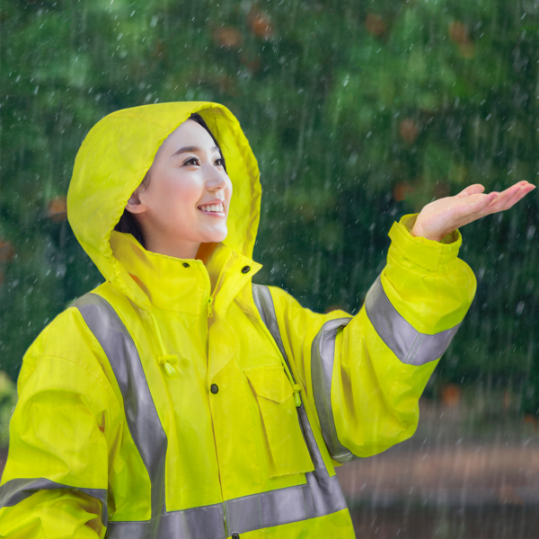 Una mujer lleva el impermeable de alta visibilidad JORESTECH recubierto de PU mientras se encuentra bajo la lluvia