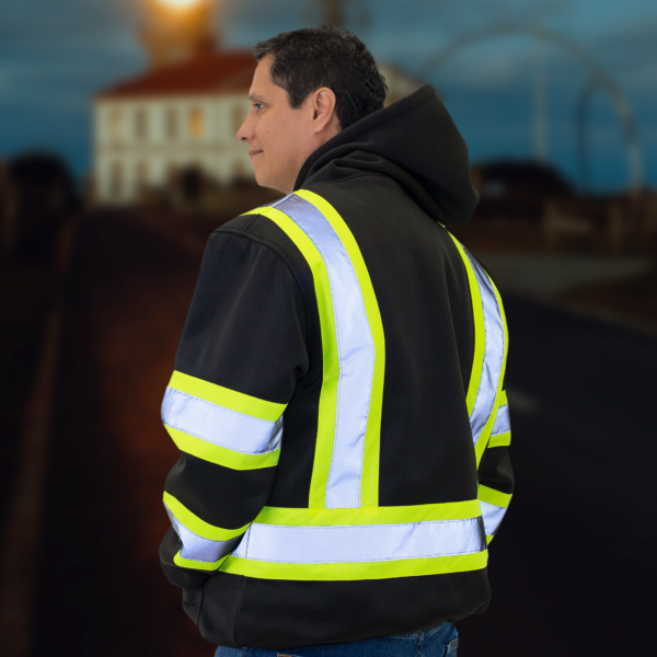 Hombre usando la sudadera con capucha de seguridad negra JORESTECH con franjas reflectantes en un entorno oscuro