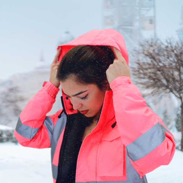 Mujer en la nieve usando la chaqueta de seguridad de alta visibilidad en rosa con bandas reflectantes