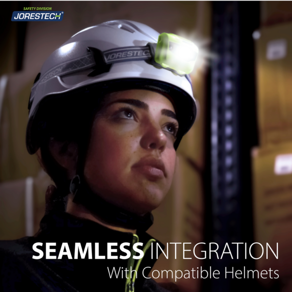 Mujer que lleva un casco blanco con una lámpara frontal verde lima compatible. El texto dice: integración perfecta con cascos compatibles. Está en un entorno donde la principal fuente de luz es la lámpara frontal.