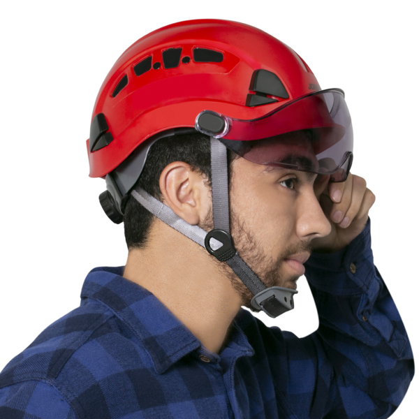 Hombre con un casco rojo y un protector ocular ahumado JORESTECH® instalado en el casco, el hombre está levantando el protector ocular hacia arriba, alejándolo de su rostro