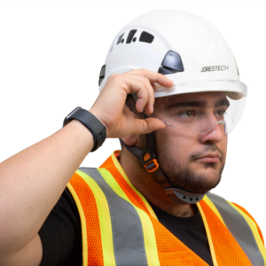 Trabajador con un casco blanco con el protector ocular JORESTECH instalado. El hombre está sujetando el protector ocular para cascos para alejarlo de su rostro.