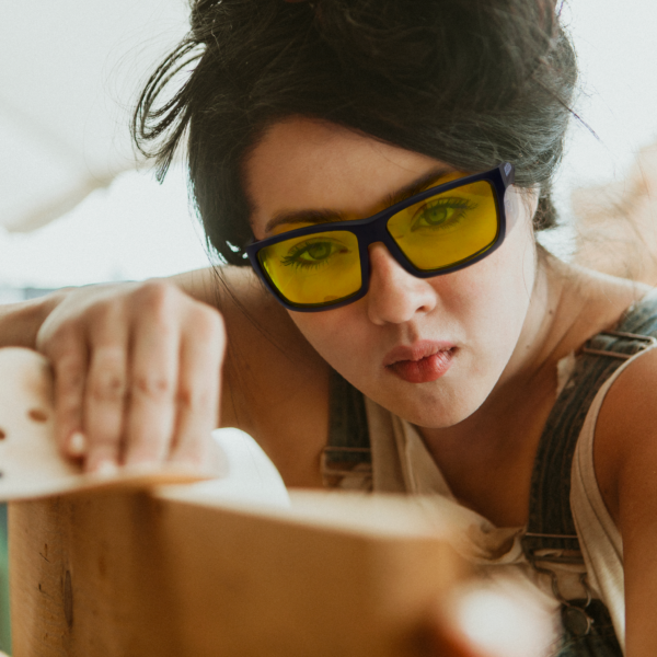Imagen de una mujer que lleva las gafas de seguridad amarillas JORESTECH con protectores laterales para protección contra impactos fuertes mientras esculpe una gran pieza de madera en un proyecto de bricolaje