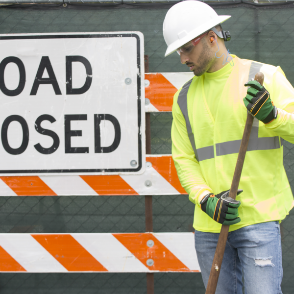 Un trabajador vial que lleva casco blanco, gafas de seguridad y los guantes de trabajo de seguridad JORESTECH con palmas de silicona antideslizante con puntos, mientras realiza trabajos de construcción de carreteras