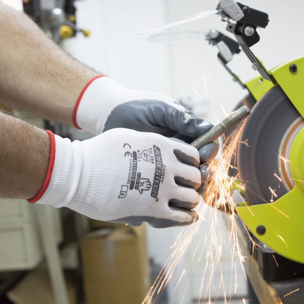 Trabajador usando los guantes de trabajo de seguridad JORESTECH con palmas recubiertas de nitrilo mientras realiza un proyecto de bricolaje con herramientas eléctricas