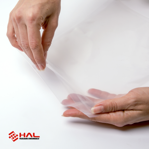 Manos de una mujer abriendo una bolsa transparente para mostrar el material de las bolsas para selladora al vacío HAL sobre fondo blanco