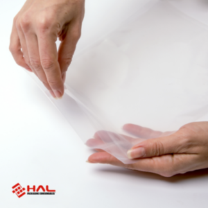Manos de una mujer abriendo una bolsa transparente para mostrar el material de las bolsas para selladora al vacío HAL sobre fondo blanco