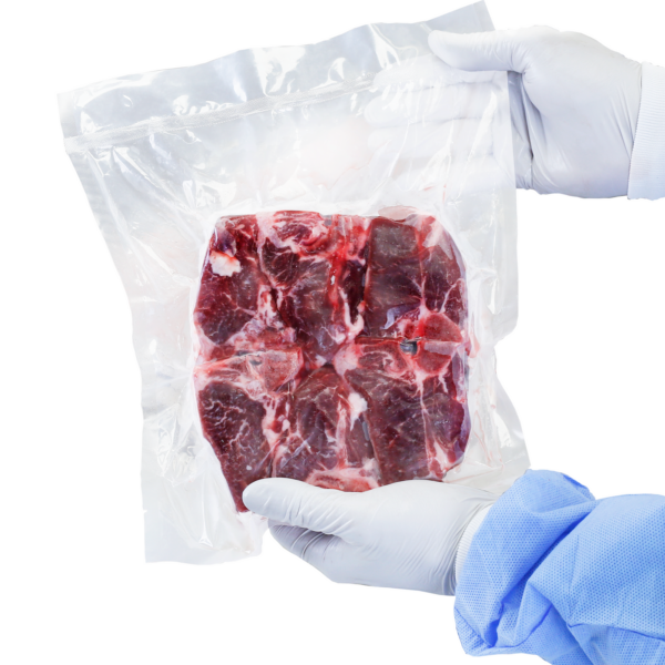 La imagen muestra a una persona sosteniendo una bolsa sellada al vacío con un gran trozo de carne cruda en su interior. La persona lleva ropa desechable.