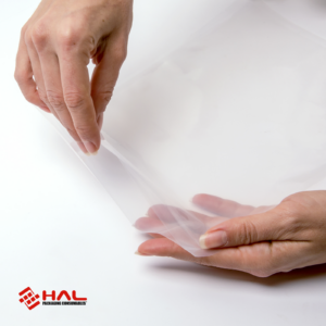 Manos de una mujer abriendo una bolsa transparente para mostrar el material de las bolsas para selladora al vacío HAL sobre fondo blanco
