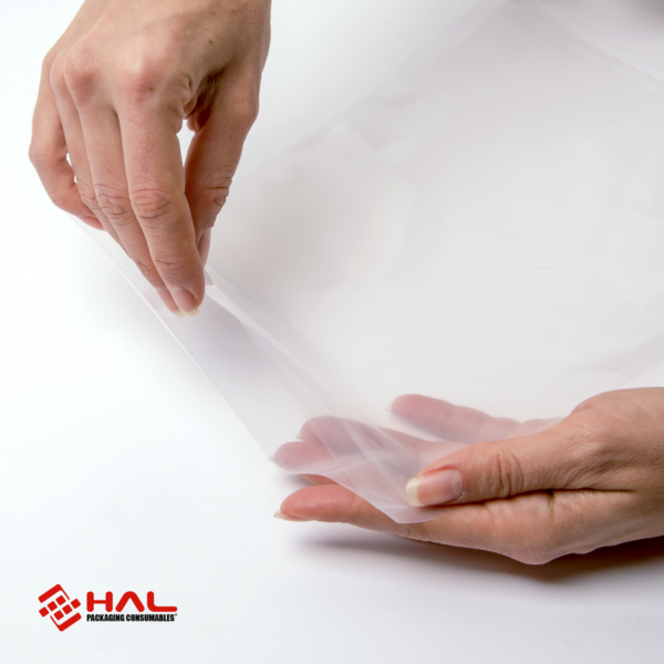 Manos de una mujer abriendo una bolsa transparente para mostrar el material de las bolsas para selladora al vacío HAL sobre fondo blanco