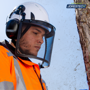 Un arborista cortando algunas ramas mientras usa el casco de seguridad ventilado blanco JORESTECH con protector facial de malla de hierro y orejeras acopladas.