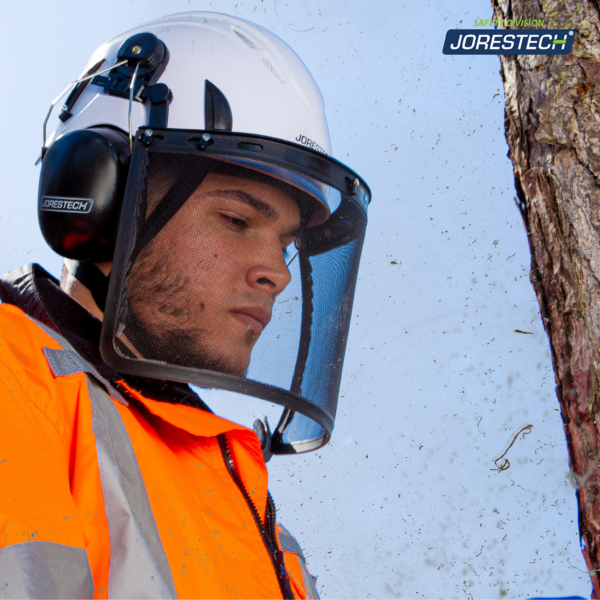 Un arborista cortando algunas ramas mientras usa el casco de seguridad ventilado blanco JORESTECH con protector facial de malla de hierro y orejeras acopladas.