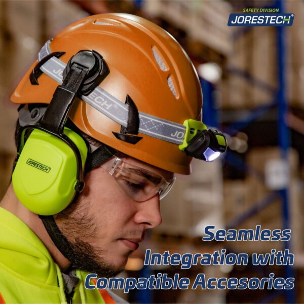 un trabajador en un entorno de almacén usando el casco de escalada ventilado naranja con un texto azul que dice: Integración perfecta con accesorios compatibles. El casco tiene una linterna frontal negra acoplada, así como un par de orejeras color lima