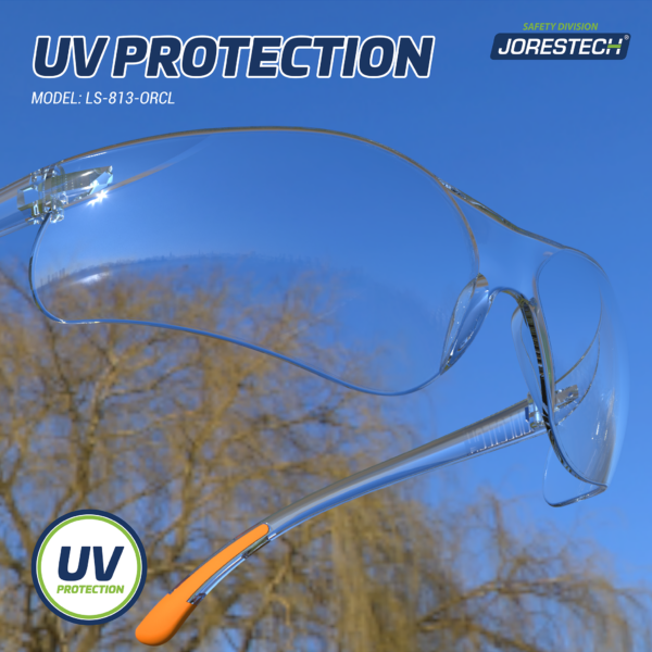 Vista de cerca de las gafas de seguridad Jorestech transparentes de alto impacto con un fondo de cielo azul y ramas de árboles. El texto dice: protección UV, modelo S-LS-813-ORCL